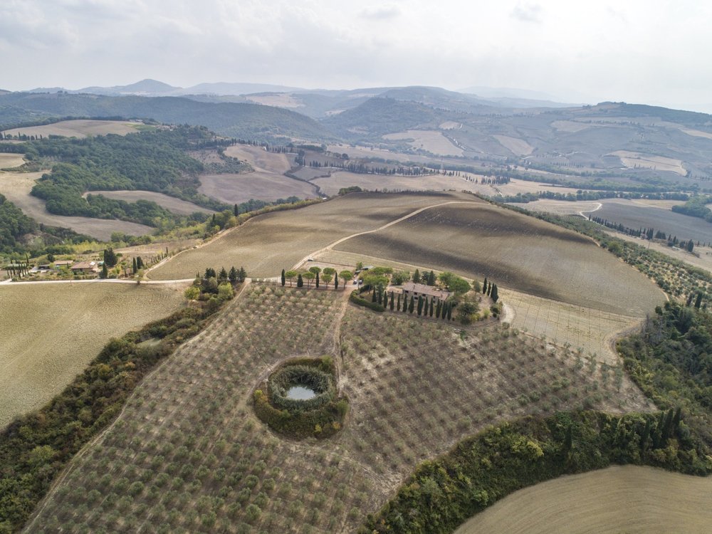 Vista aerea di un casale con oliveto, stagno e terreni collinari
